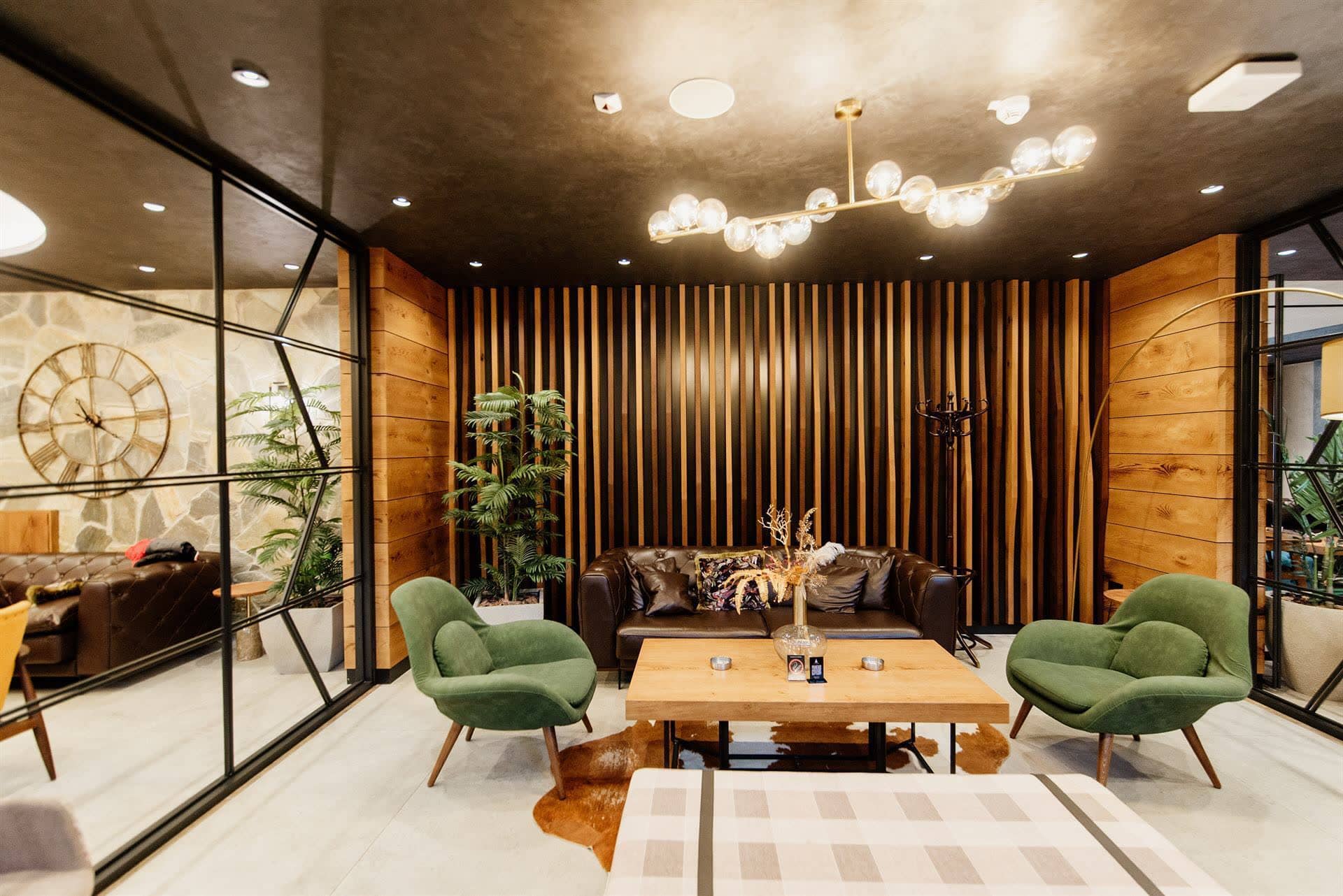 Furnished lounge with green armchairs and a leather sofa